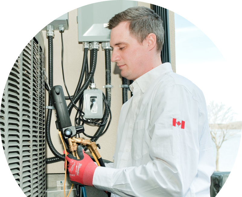 Wardlaw technician servicing an outdoor air conditioner using a digital refrigerant tool, wearing red gloves and a white uniform. Wardlaw technician servicing an outdoor air conditioner using a digital refrigerant tool, wearing red gloves and a white uniform.