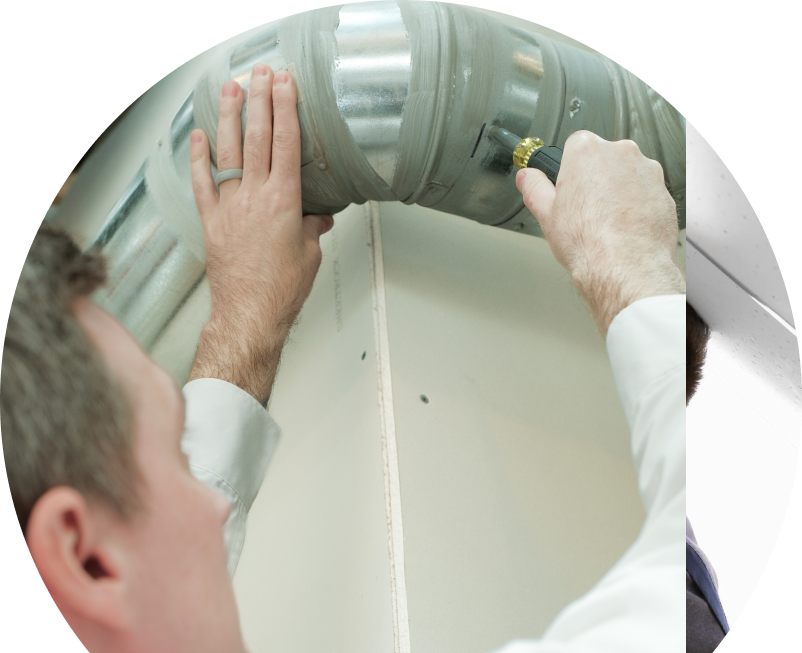 Wardlaw HVAC technician inspecting and tightening a joint on a sealed metal air duct, performing maintenance work during an air duct cleaning task. Wardlaw HVAC technician inspecting and tightening a joint on a sealed metal air duct, performing maintenance work during an air duct cleaning task.