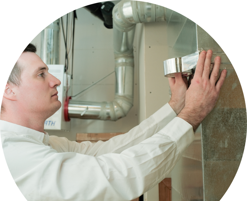 A Wardlaw HVAC personnel securing air ducting with foil tape during an air duct installation in a residential utility space with visible metal ventilation lines.