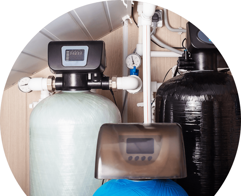 Wardlaw home water filtration system featuring resin tanks, digital control heads, pressure gauges, and connected piping in a utility room. Wardlaw home water filtration system featuring resin tanks, digital control heads, pressure gauges, and connected piping in a utility room.