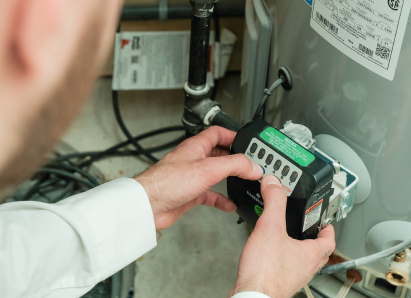 A Wardlaw technician adjusts the control module on a residential water heater, verifying proper operating settings. A Wardlaw technician adjusts the control module on a residential water heater, verifying proper operating settings.