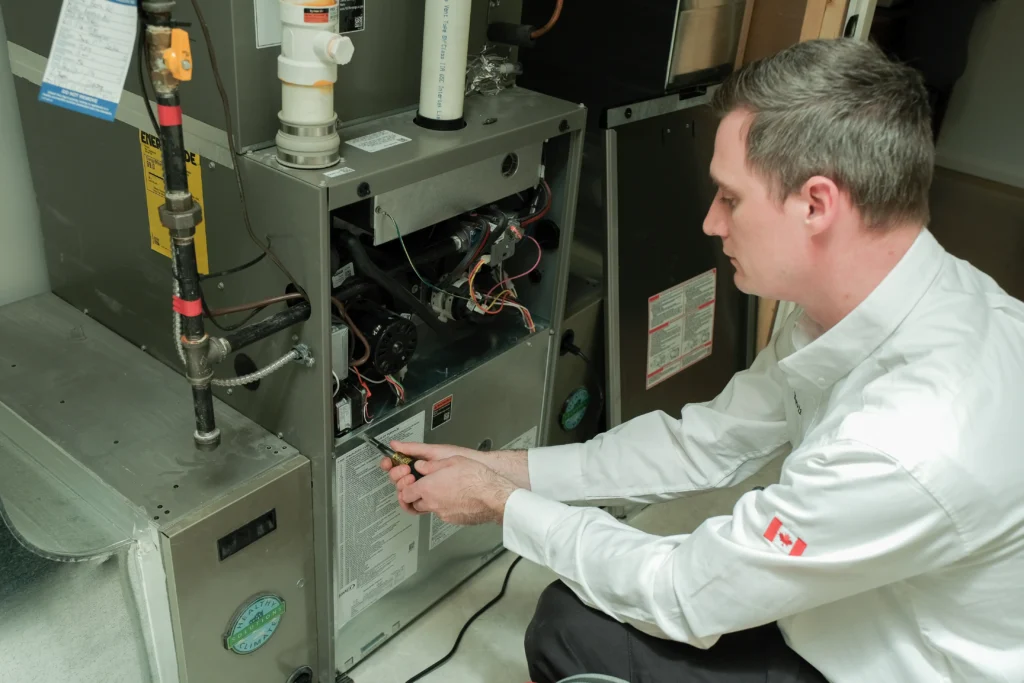 Wardlaw technician inspecting a high-efficiency furnace cabinet to prevent wind-related draft shutdowns in a Sault Ste. Marie's home.
